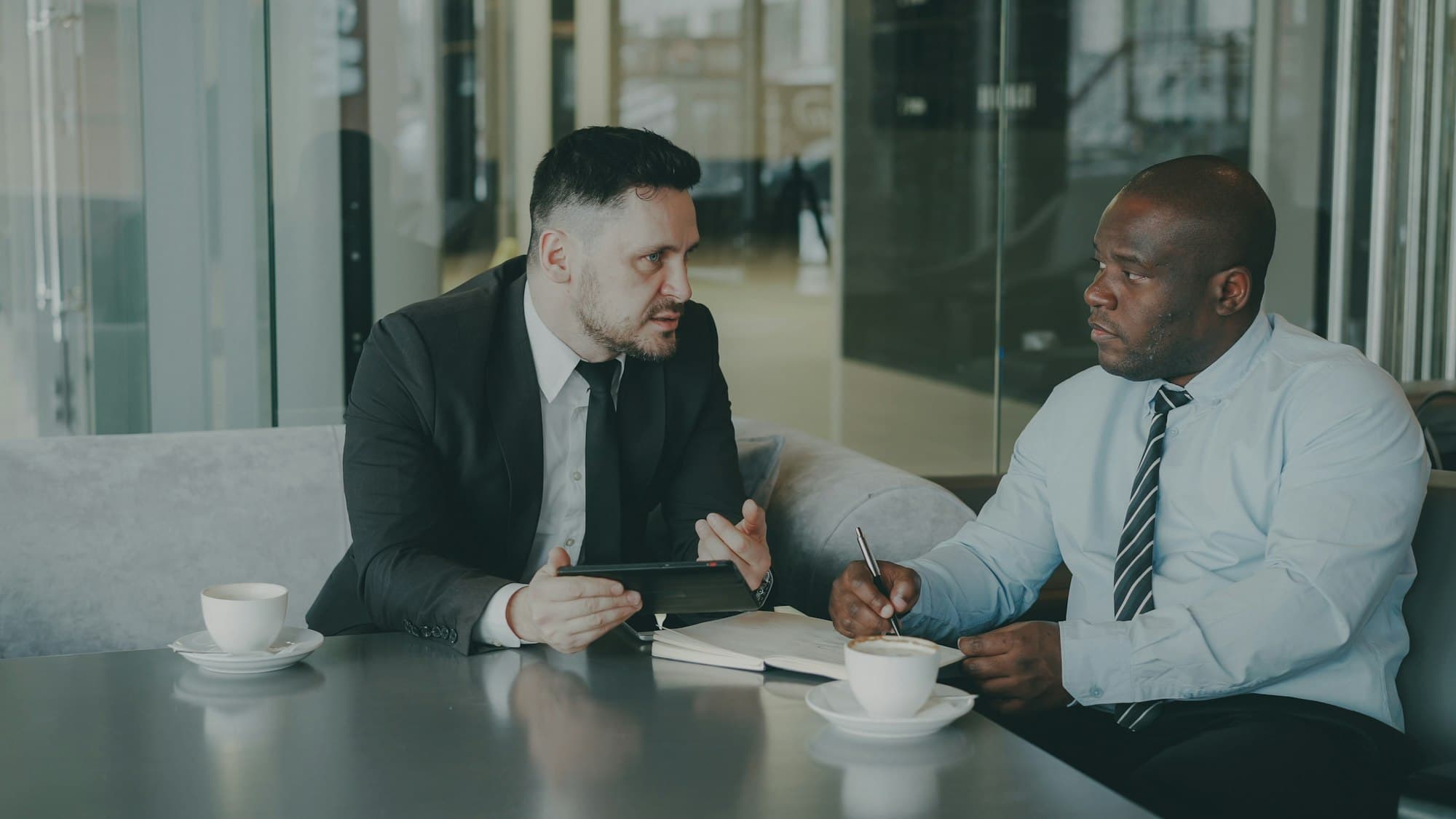 Two executives in a focused coaching conversation over coffee
